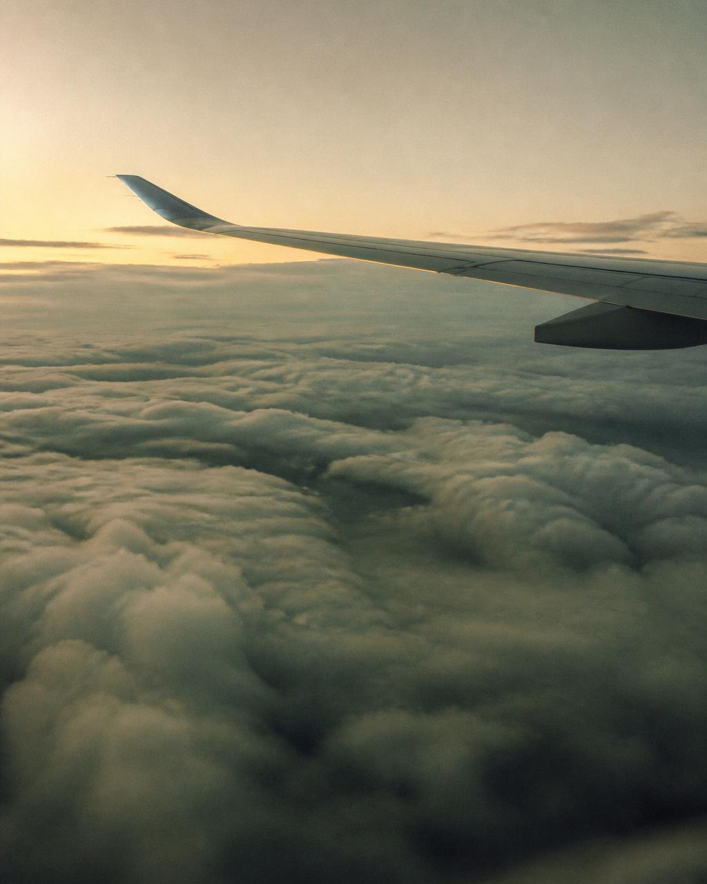 Vista da asa de uma aeronave acima das nuvens ao amanhecer